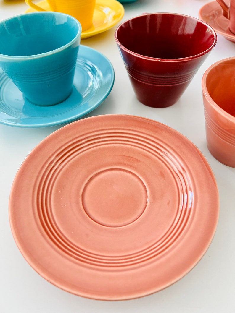 Puede incluir: Un juego de cinco tazas de t&eacute; vintage y platillos en varios colores, incluyendo azul, rojo, amarillo y rosa. Los platillos tienen un dise&ntilde;o simple y elegante con un patr&oacute;n de c&iacute;rculos conc&eacute;ntricos.