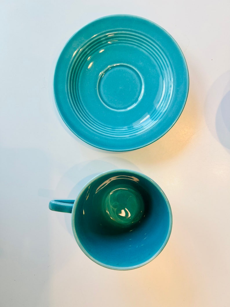 Puede incluir: Un juego de taza y platillo de color azul turquesa. El platillo tiene un dise&ntilde;o acanalado y la taza tiene un interior liso.