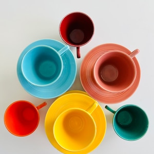 Puede incluir: Seis tazas de t&eacute; y platillos coloridos en un patr&oacute;n de arco&iacute;ris. Las tazas y los platillos est&aacute;n dispuestos en un c&iacute;rculo sobre un fondo blanco. Los colores son rojo, naranja, amarillo, verde, azul y rosa.