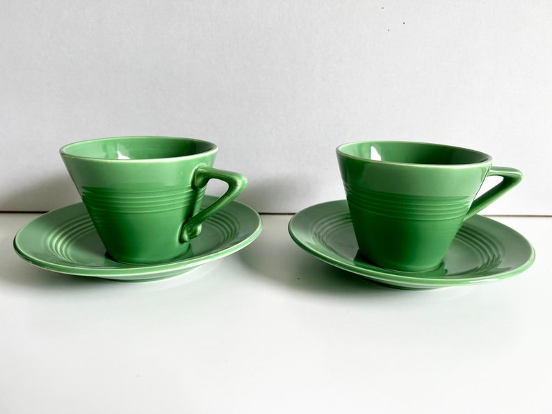 Puede incluir: Dos tazas de t&eacute; verdes y platillos. Las tazas son de color verde claro y tienen un dise&ntilde;o simple. Los platillos son blancos con un borde verde.