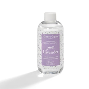 May include: A clear glass bottle with a white cap filled with a lavender-scented reed diffuser refill. The bottle has a label with the text "Hassett Green London" and "just Lavender" in purple lettering. The label also states "A Fresh Herbaceous and Soothing Lavender Scent" and "250ml e 8.45 US fl.oz."