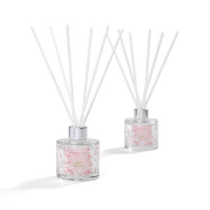 May include: Two glass reed diffusers with silver lids and white reeds. The bottles feature a floral design and the words "Apple Blossoms". The diffusers are set against a white backdrop.