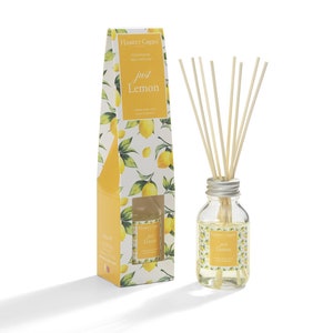 May include: A glass bottle diffuser with a silver lid and wooden sticks. The bottle is filled with a clear liquid and has a label that says "Hassett Green London Fragranced Reed Diffuser Just Lemon". The bottle is sitting on a white surface with a yellow and white box behind it. The box has a picture of lemons on it.