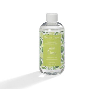 May include: Clear glass bottle with a white lid and a green label that says "HASSETT GREEN LONDON FRAGRANCED REED DIFFUSER REFILL just Lime A fresh zingy and zesty lime fragrance 250ml e 8.45 US fl.oz". The bottle is filled with a clear liquid and has a design of green limes on the label.