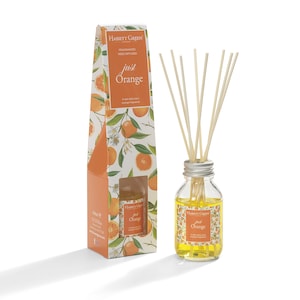 May include: A reed diffuser with a clear glass bottle and a silver cap. The bottle is filled with a yellow liquid and has a label that says "Hassett Green" and "Just Orange". The diffuser comes with a set of wooden reeds.