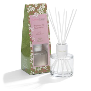 May include: A clear glass bottle with a white lid and white reeds, filled with a clear liquid. The bottle is labelled "Hassett Green London" and "Apple Blossom". The bottle is in a box with a floral design.