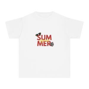 Op de afbeelding: Een wit T-shirt met korte mouwen en de rode tekst "SUMMER" met het gele woord "squad" er diagonaal overheen geschreven. Het ontwerp bevat kleine illustraties van blauwe en oranje tropische bloemen en een groen monstera-blad.