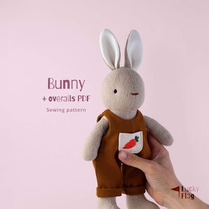 Könnte beinhalten: Ein Stofftier-Hase mit brauner Latzhose und Karottentasche. Der Hase hat lange Ohren und eine aufgenähte Nase und Mund. Der Text auf dem Bild lautet "Bunny + overalls PDF Sewing pattern".