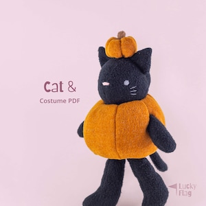 May include: A black plush cat toy wearing an orange pumpkin costume around its body and a small pumpkin on its head. The text Cat & Costume PDF is visible on the left, and the text Lucky Flag is visible in the bottom right corner.