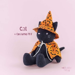 May include: A black plush cat toy wearing an orange witch hat and cape with a black bat pattern. The text Cat + Costume PDF is visible on the left, and the text Lucky Flag is in the bottom right corner. The cat has embroidered facial features.