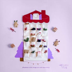 Peut inclure: Un calendrier de l'Avent en forme de maison avec 24 poches, un toit rouge et des accents d'arbres violets. Les poches contiennent de petits jouets en peluche, des cadeaux et de la verdure. Le texte en bas indique "(Les peluches sur cette image sont vendues séparément)".