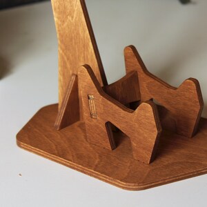 May include: A wooden stand for holding a guitar. The stand is made of light brown wood and has a simple design.