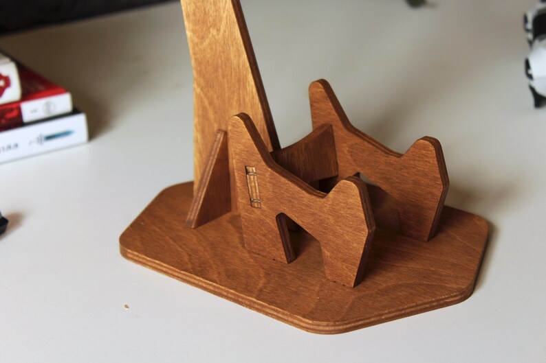 May include: A wooden stand for holding a guitar. The stand is made of light brown wood and has a simple design.
