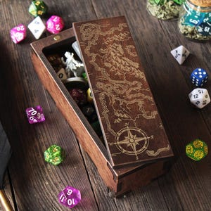 Puede incluir: Una caja de madera con una tapa con bisagras que presenta un mapa de Poniente, un continente ficticio de la serie Juego de Tronos. La caja está llena de dados y figuras en miniatura.