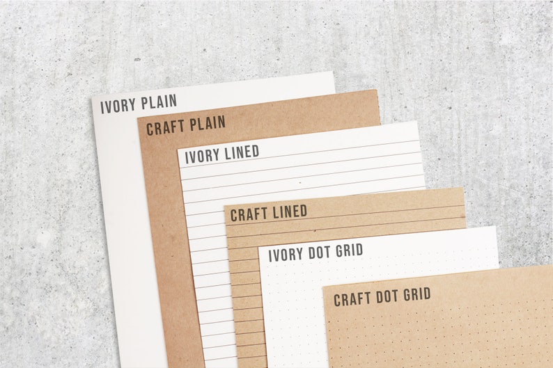 May include: Six different paper pads, two in ivory and four in brown craft paper. The ivory pads are labeled "Ivory Plain", "Ivory Lined", and "Ivory Dot Grid". The brown craft pads are labeled "Craft Plain", "Craft Lined", and "Craft Dot Grid".