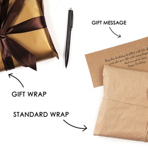 May include: Two gift wrapping options are shown. One is a gold gift wrap with a brown ribbon. The other is a brown paper gift wrap with twine. A handwritten gift message is included on a brown card. The message reads: "May this birthday be filled with lots of happy hours and also your life with many happy birthdays that are yet to come. Happy Birthday."
