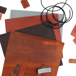May include: A collection of leather pieces for crafting, including various sizes of brown leather squares, a brown leather rectangle, a gray leather rectangle, a black leather rectangle, a brown leather rectangle with holes, a brown leather rectangle with holes and a white thread, and a brown leather rectangle with holes and a white thread.