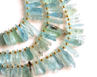 May include: Two strands of aquamarine gemstone beads, each strung with gold spacer beads. The aquamarine beads are faceted and have a light blue to green color.