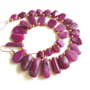 May include: A strand of pink gemstone beads with gold spacers. The beads are irregular in shape and have a smooth, polished finish.