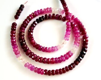 May include: A strand of faceted ruby beads in shades of pink, red, and purple. The beads are graduated in size, with the smaller beads at one end and the larger beads at the other. The beads are strung on a wire.