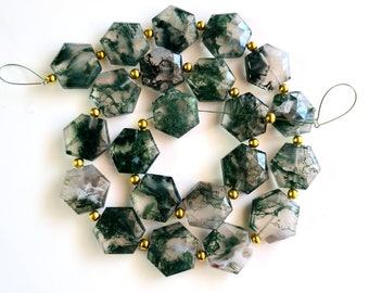 May include: A strand of moss agate beads with a green and white marbled pattern. The beads are faceted and have a hexagonal shape. The strand is strung with gold-colored spacers.