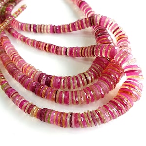 May include: A strand of pink, green and yellow gemstone beads. The beads are faceted and have a slightly irregular shape. The beads are strung on a clear thread.