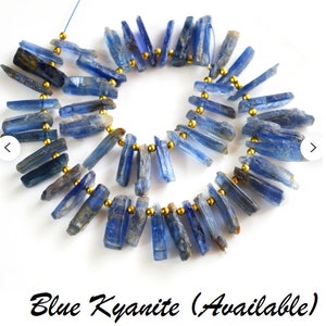 May include: A strand of blue kyanite gemstone beads strung on gold wire. The beads are long and slender, with a slightly rough texture.  Blue Kyanite (Available)