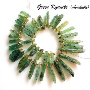 May include: A strand of green kyanite gemstone beads, strung on a wire with gold spacers. The beads are long and slender, with a natural, rough texture. Green Kyanite (Available)
