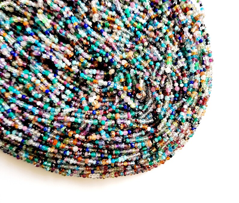 May include: A strand of colorful gemstone beads, including blue, green, purple, and brown, with a variety of shapes and sizes.