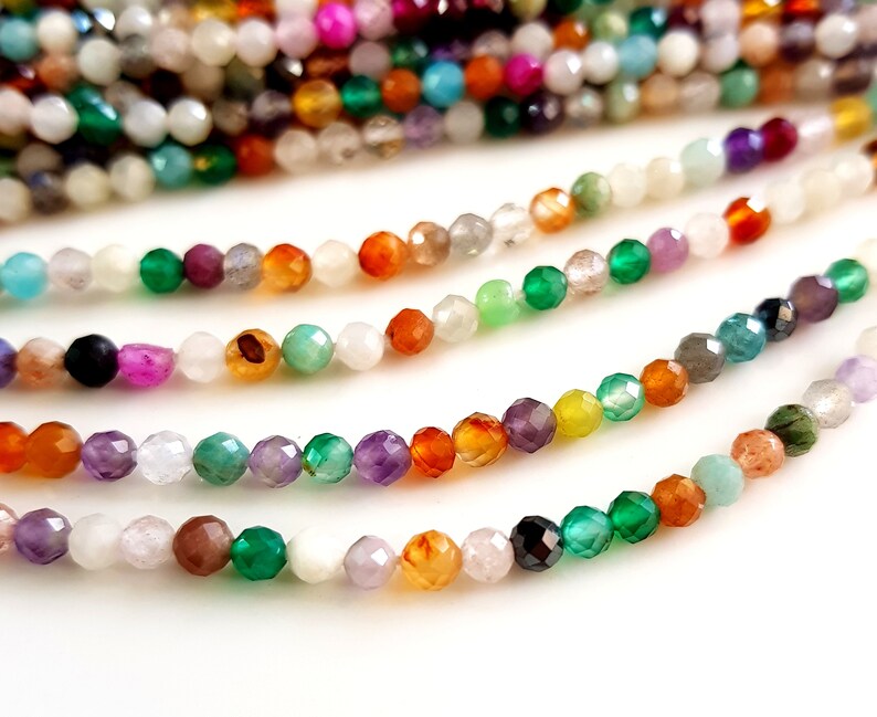 May include: Strands of faceted gemstone beads in a variety of colors, including green, orange, purple, and white. The beads are small and strung together, creating a colorful and textured appearance. Ideal for jewelry making.