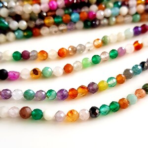 May include: Strands of faceted gemstone beads in a variety of colors, including green, orange, purple, and white. The beads are small and strung together, creating a colorful and textured appearance. Ideal for jewelry making.