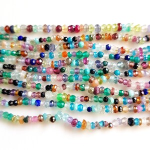 May include: A strand of colorful gemstone beads, including green, blue, red, and purple beads. The beads are faceted and have a variety of shapes and sizes.