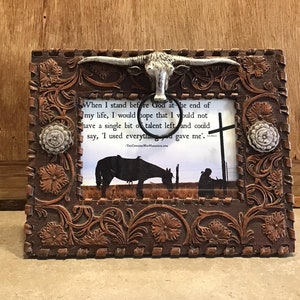 May include: A brown leather picture frame with a tooled design and a silver steer head. The frame has a quote inside that reads: "When I stand before God at the end of my life, I would hope that I would not have a single bit of talent left and could say, 'I used everything you gave me.'"