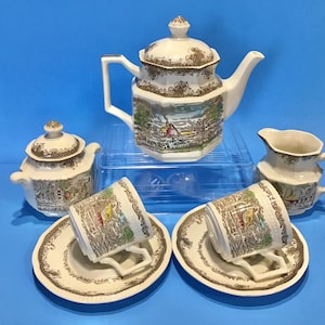 May include: A vintage tea set with a brown and white floral pattern. The set includes a teapot, creamer, sugar bowl, and two teacups and saucers.