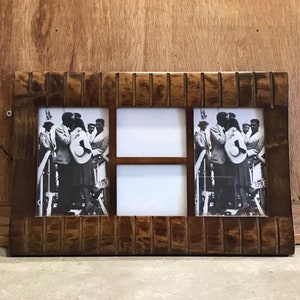 May include: A wooden picture frame with a dark brown finish. The frame has four openings for photos, each with a white mount. The frame is decorated with a raised, grooved design around the edges. The frame is displaying black and white photos of people.