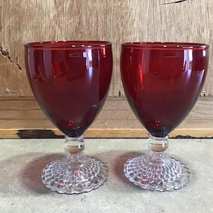 2 Vintage ruby glass goblets on clear graduated hobnail pedestal bases.