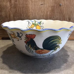 May include: A white ceramic bowl with a scalloped rim features a colorful rooster design with yellow, blue, green, and red accents. The bowl is decorated with a rooster, flowers, and lemons.