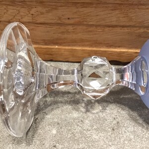 May include: The bottom of a clear glass goblet with a frosted blue bowl. The stem is faceted and has a round knob.
