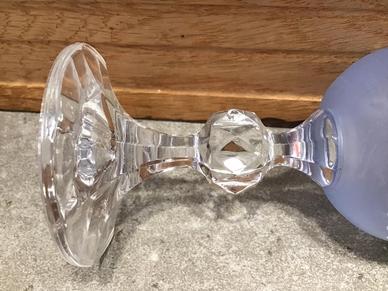 May include: The bottom of a clear glass goblet with a frosted blue bowl. The stem is faceted and has a round knob.