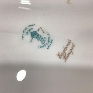 May include: Close-up of a white ceramic plate with a green and gold logo that reads "Fine Bone China Crown Est. 1801 Staffs.  Eng.  England's Bouquet".