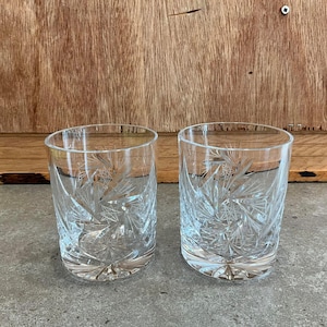 Puede incluir: Dos vasos transparentes de vidrio con un diseño de vidrio cortado. Los vasos tienen un patrón de estrella.