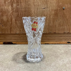May include: A clear glass vase with a cut crystal design. The vase has a label that reads "Anna-Home  Lead Crystal  GUARANTEED".
