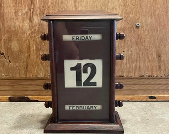 An early 20th century replica perpetual desk calendar, with three glazed apertures for day, date and month