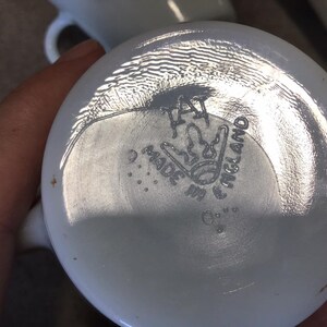 Pode incluir: Caneca de cer&acirc;mica branca com um logotipo preto e branco que diz "Made in England" e uma coroa.