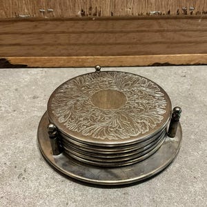 Set med 6 stapelbara vintage-drickunderlägg i metall och hållare med bas i silverpläterat mönster