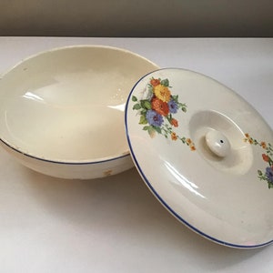 Könnte beinhalten: Eine weiße Keramikschüssel mit blauem Rand und Blumenmuster. Die Schüssel hat einen passenden Deckel mit einem Knopf oben.
