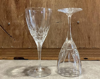 May include: Two clear glass wine glasses, one with a traditional bowl shape and the other with a wider, more rounded bowl. Both glasses have a delicate, etched design.