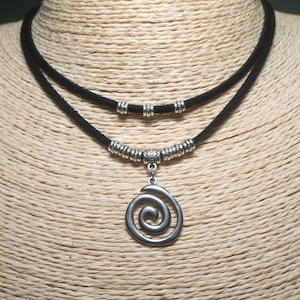 May include: A double-strand black cord necklace with silver-coloured metal beads and a spiral pendant. The necklace is displayed on a mannequin. A fashion accessory.