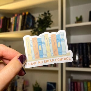 May include: A sticker with a row of colorful books and the text "I HAVE NO SHELF CONTROL".