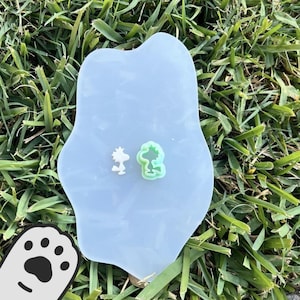 May include: A white and green silicone mold featuring two cartoon characters. The mold is on a white surface.